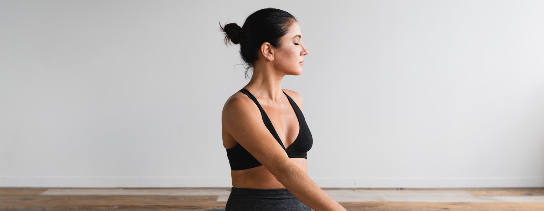 lifestyle image of a woman in a yoga pose and in a bright space